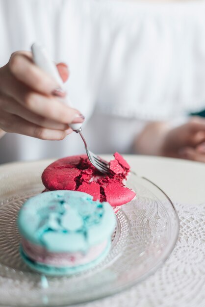 La mano de la mujer que come el emparedado del helado con la bifurcación en la placa transparente de cristal