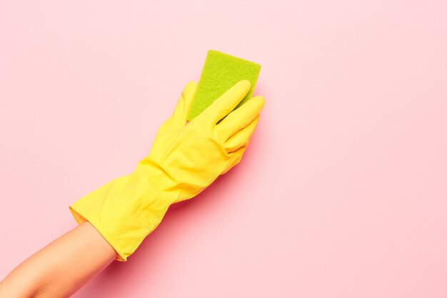 La mano de la mujer que limpia en una pared rosada. Concepto de limpieza o limpieza