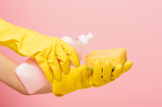 La mano de la mujer que limpia en una pared rosada. Concepto de limpieza o limpieza