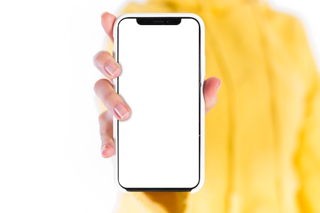 Mano de la mujer que muestra el teléfono móvil con pantalla blanca en blanco