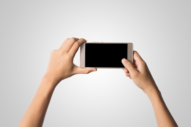 Mano de la mujer que sostiene la pantalla en blanco del teléfono elegante. Copie el espacio. Mano que sostiene el smartphone aislado en el fondo blanco.