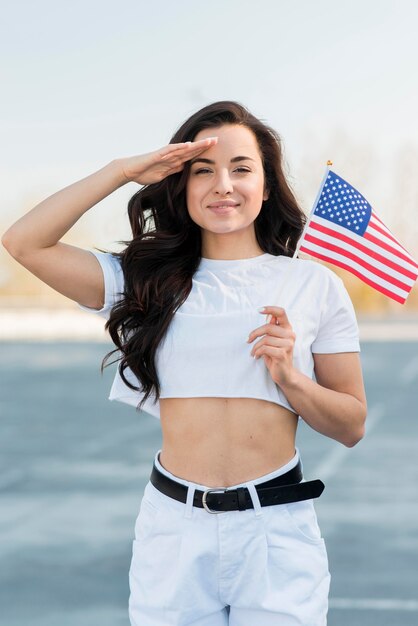 Mano de mujer saludando y sosteniendo la bandera de Estados Unidos