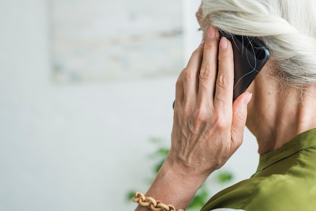 Foto gratuita mano de mujer senior con teléfono móvil