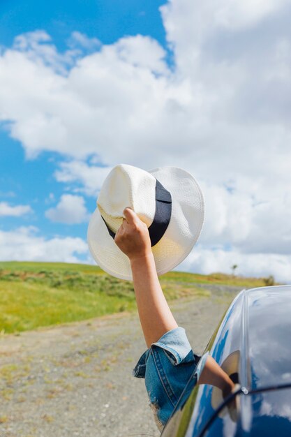 Mano de mujer con sombrero contra el cielo