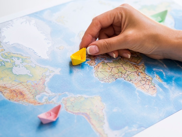 Mano de mujer sosteniendo un barco de papel en un mapa