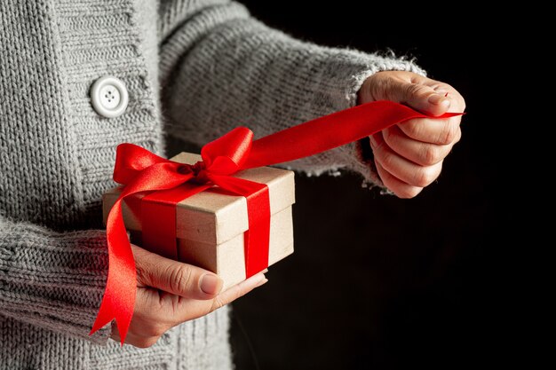 Mano de mujer sosteniendo una caja de regalo con cinta roja