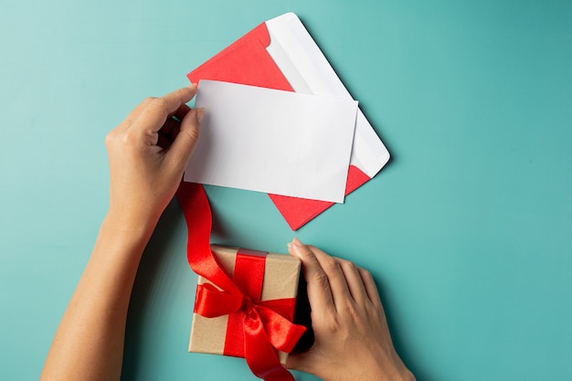 Mano de mujer sosteniendo caja de regalo y tarjeta de felicitación