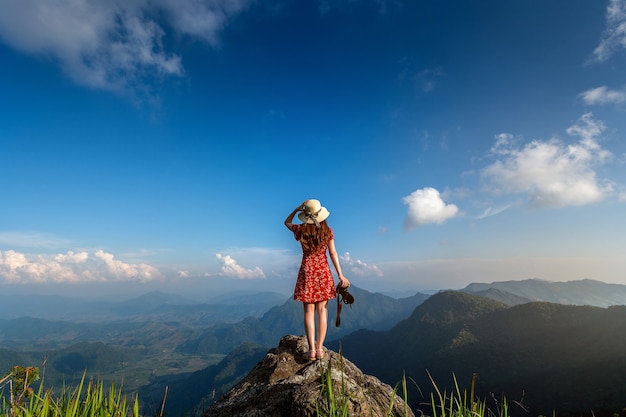 Mano de mujer sosteniendo la cámara y de pie en la cima de la roca en la naturaleza. Concepto de viaje.