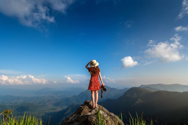 Mano de mujer sosteniendo la cámara y de pie en la cima de la roca en la naturaleza. Concepto de viaje.