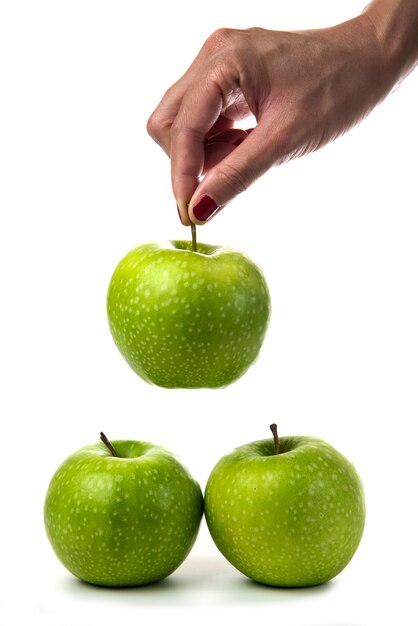 Mano de mujer sosteniendo manzanas verdes sobre blanco.