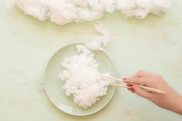 Foto gratuita mano de mujer sosteniendo nube blanca con palillos