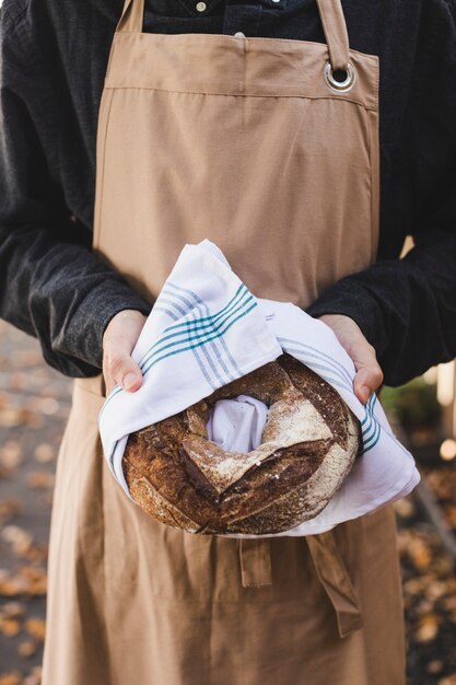 La mano de una mujer sosteniendo pan de pan grande envuelto en una servilleta blanca