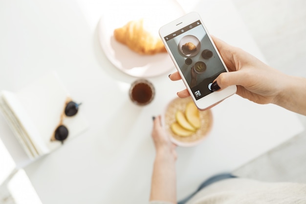 Mano de mujer sosteniendo el pulgar en la pantalla, disparando comida. Fotografía de alimentos.