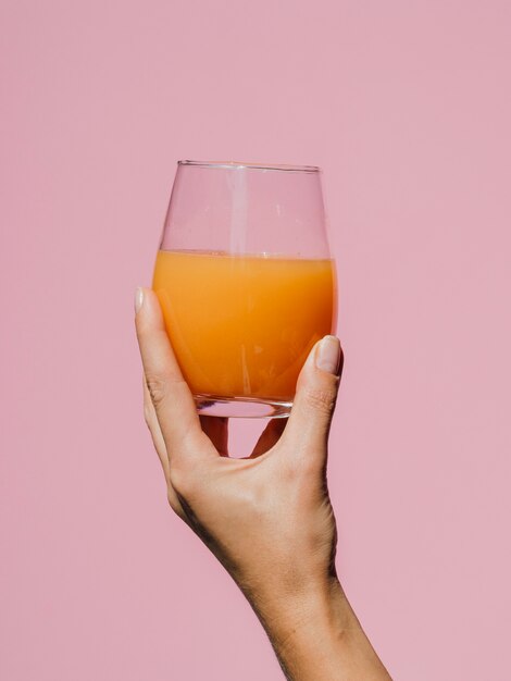 Mano de mujer sosteniendo un sabroso vaso de jugo