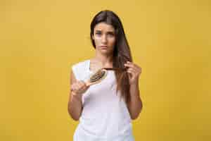 Foto gratuita mano de mujer sosteniendo su cabello largo con mirar las puntas divididas dañadas de los problemas de cuidado del cabello.