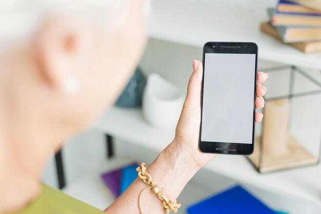 Mano de mujer sosteniendo teléfono inteligente con pantalla en blanco
