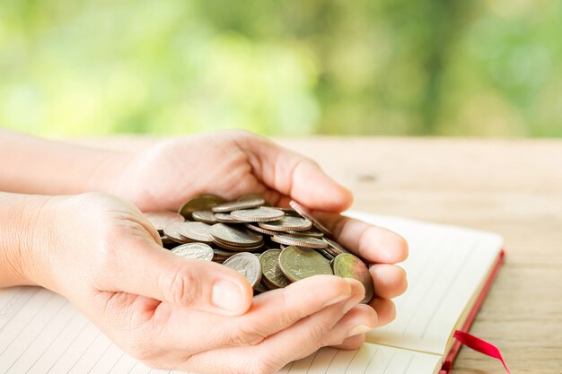 La mano de la mujer sostiene muchas monedas.