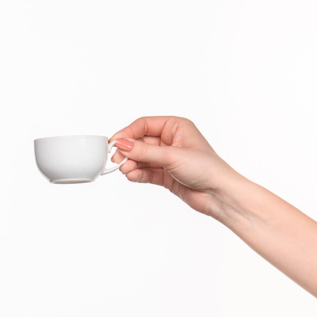 Mano de mujer con taza blanca perfecta sobre fondo blanco.