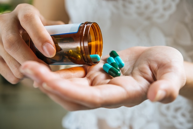 Mano de mujer vierte las pastillas de la medicina fuera de la botella