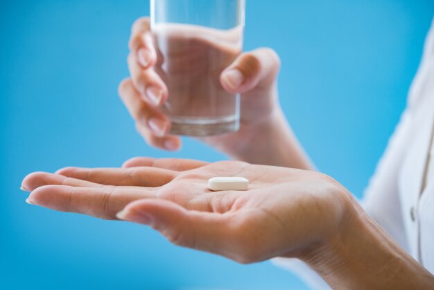 Mano de mujer vierte las pastillas de la medicina fuera de la botella