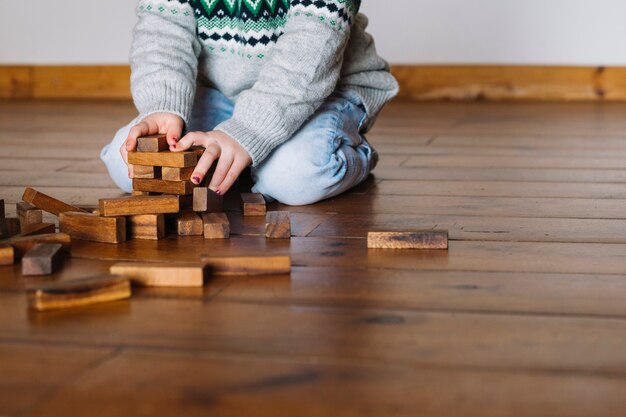 Mano de niña construyendo bloques de madera