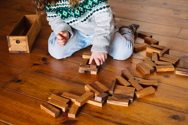 Mano de niña jugando juego de bloque de madera en casa