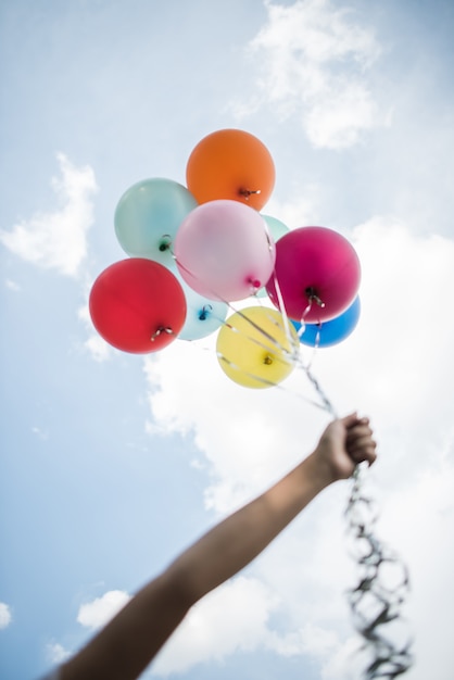 Mano de niña sosteniendo globos de colores