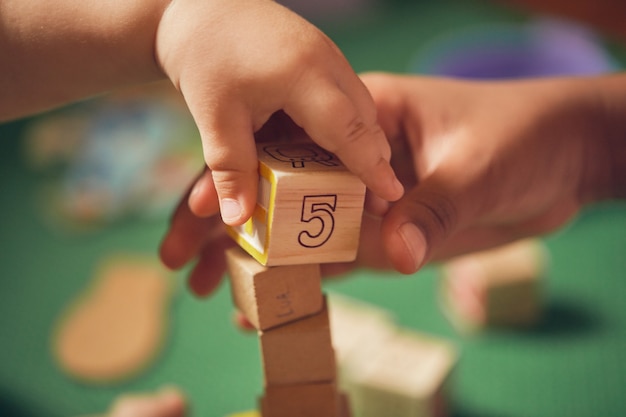 mano del niño recogiendo un bloque de madera con el número 5