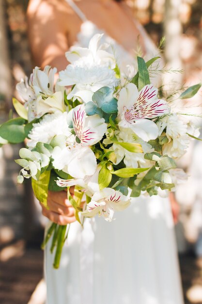 Mano de la novia con ramo de flores de lirio y gerbera peruanos en la mano