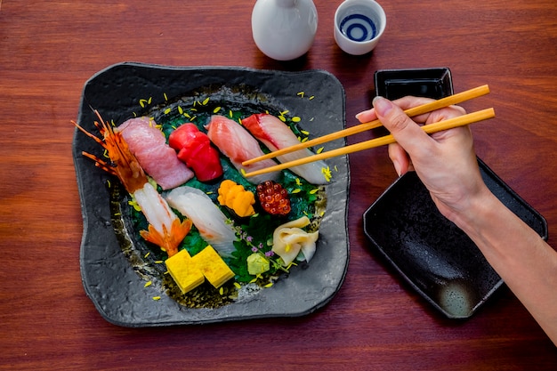 Foto gratuita mano palillo pescado crudo sushi conjunto comida japonesa