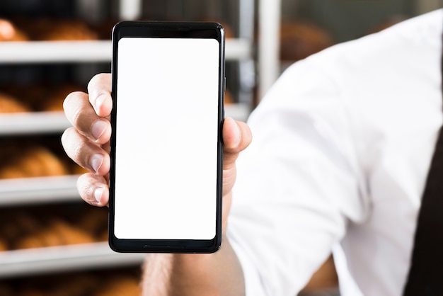 La mano de un panadero masculino que muestra la pantalla blanca del teléfono móvil