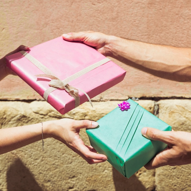 Mano de la pareja intercambiando regalo de San Valentín