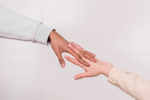 Mano de la pareja interracial contra el fondo blanco