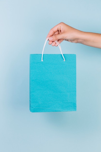 Mano de una persona con bolsa de compras de papel azul