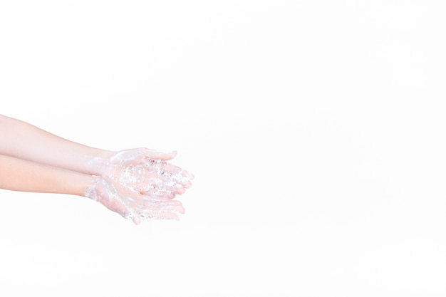 La mano de una persona en espuma de jabón sobre fondo blanco