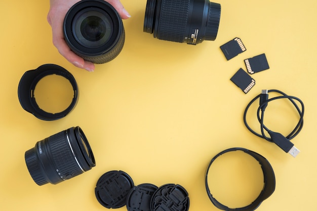 Foto gratuita mano de la persona que arregla los accesorios de la cámara en forma circular sobre fondo amarillo