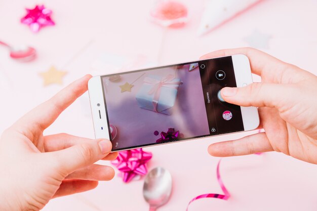 La mano de una persona que captura una foto de la celebración de cumpleaños en un teléfono inteligente