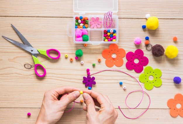 La mano de una persona que hace joyería hecha a mano con perlas y parche de flores