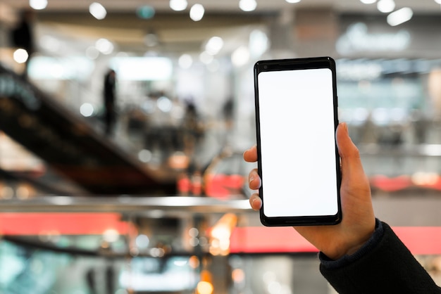 La mano de una persona que muestra la pantalla del teléfono móvil en el centro comercial