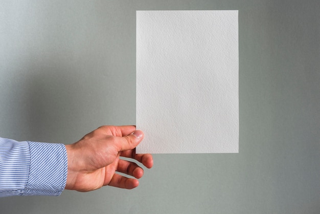 La mano de una persona que sostiene el Libro Blanco en blanco sobre fondo gris