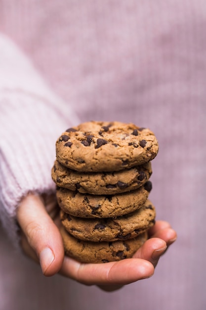 La mano de una persona que sostiene la pila de galletas de chocolate