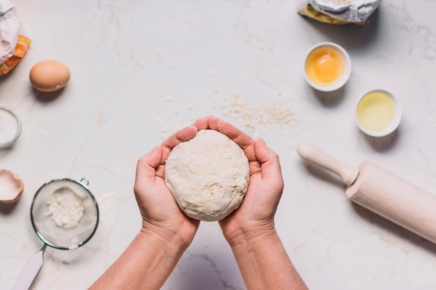 Foto gratuita la mano de una persona sosteniendo una masa con ingredientes para hornear en el mostrador de la cocina