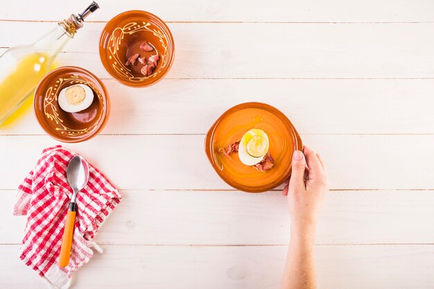 Mano con plato de sopa en la mesa de cocina