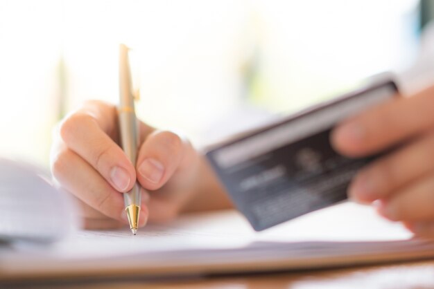 Mano con la pluma y la tarjeta de crédito sobre el formulario de aplicación.