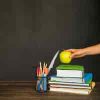 Foto gratuita mano poner apple en libros de texto en lugar de trabajo
