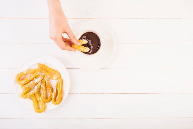 Mano poner pretzel sobre salsa de chocolate en la mesa