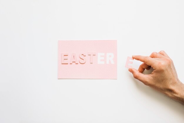 Mano poniendo palabra de Pascua en papel