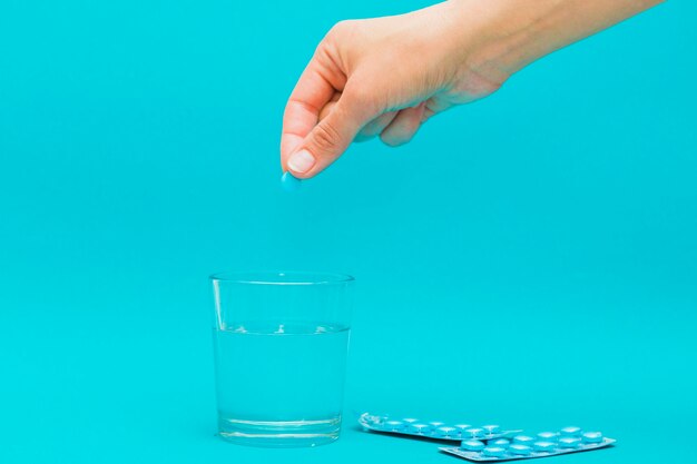 Mano poniendo pastilla en vaso de agua