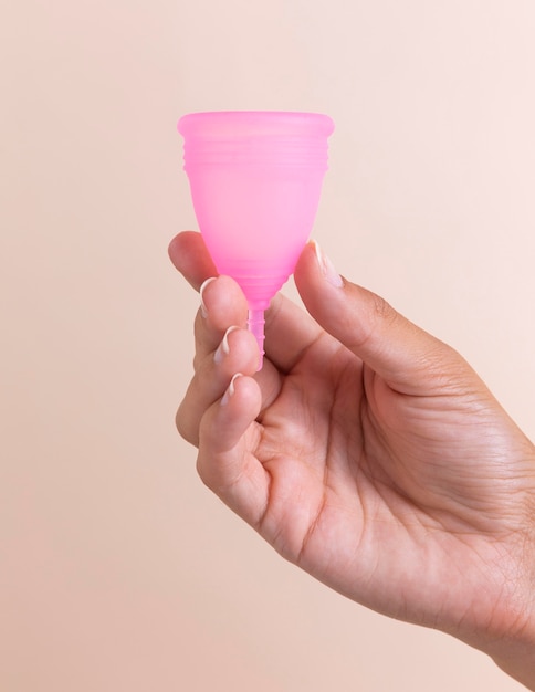 Mano de primer plano sosteniendo la copa menstrual rosa