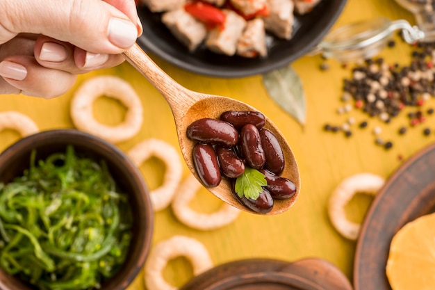 Mano de primer plano sosteniendo una cuchara con frijoles